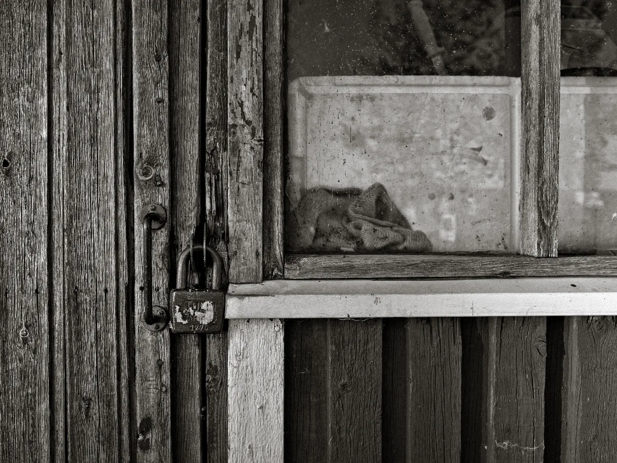 And old and dirty window and a door with an old padlock