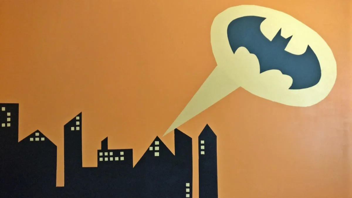 A wall with a batman mural and a city silhouette