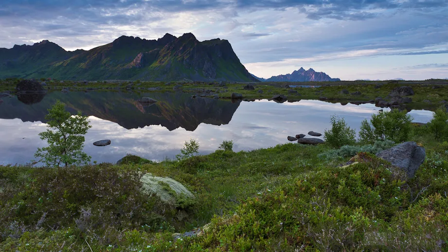 A mountain scene with a lake in the foreground during sunset