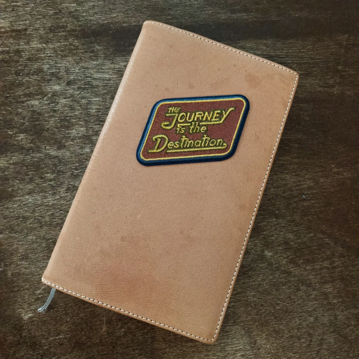 A Midori B6 slim notebook with a sticker saying The Journey is the Destination in on top